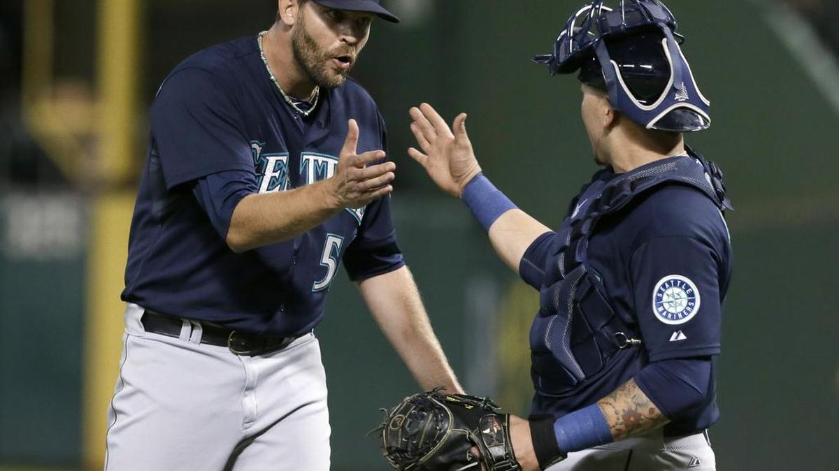 
Seattle Mariners closer Tom Wilhelmsen (54) and catcher Jesus Sucre celebrate after the final out Friday in Arlington, Texas.
