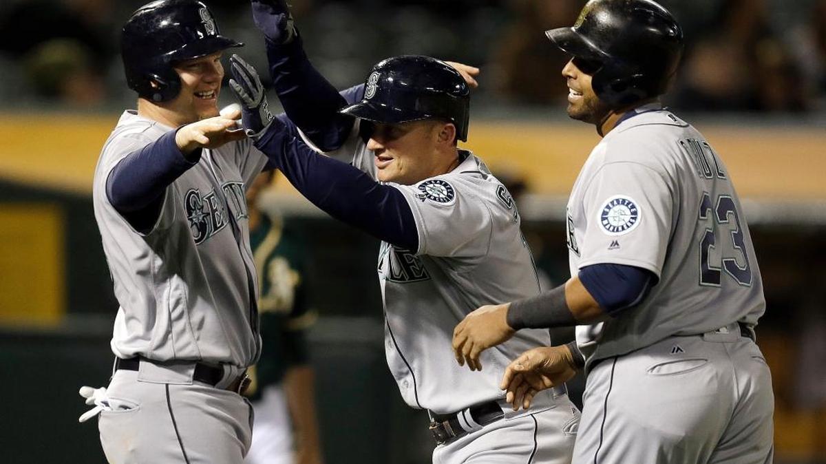 Seattle Mariners’ Kyle Seager, center, celebrates with Nelson Cruz (23) and Adam Lind, left, after hitting a three run home run off Oakland Athletics' Marc Rzepczynski in the eighth inning of a baseball game Tuesday, May 3, 2016, in Oakland, Calif.