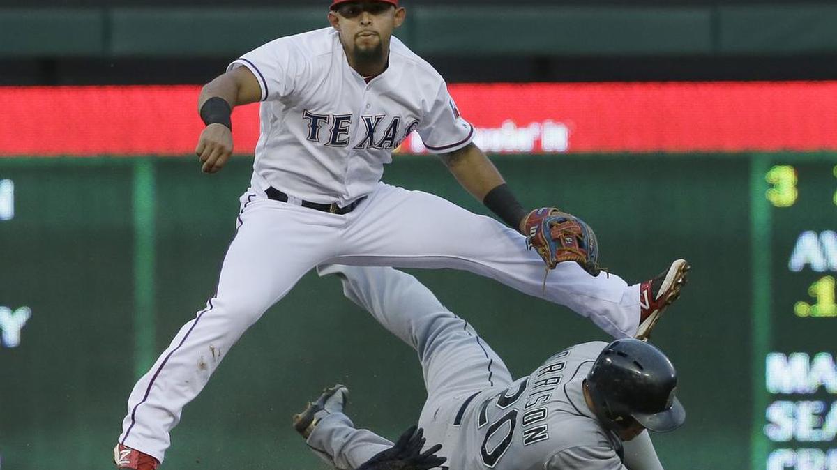
Texas second baseman Rougned Odor, top, throws to first base to complete the double play over a sliding Logan Morrison of the Mariners in the third inning Monday in Arlington, Texas.

