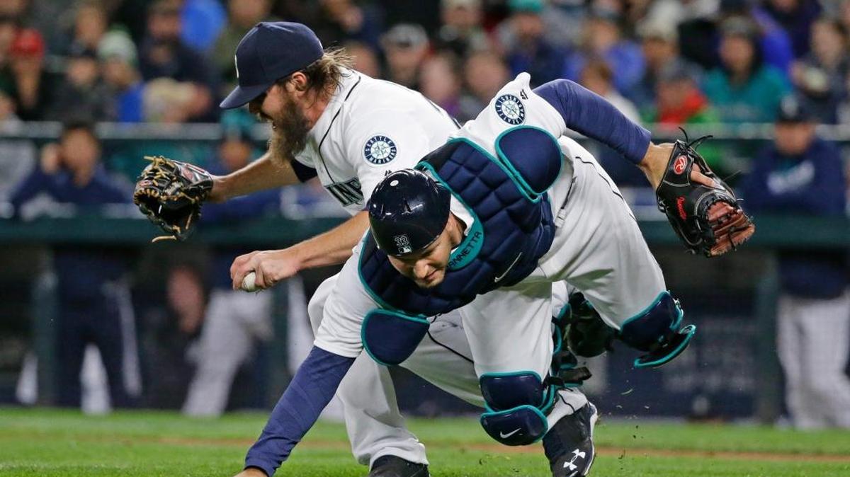 Seattle Mariners starting pitcher Wade Miley, left, reacts as he collides with catcher Chris Iannetta as they try to field a bunt single by Texas Rangers’ Delino DeShields during the third inning of a baseball game, Tuesday, April 12, 2016, in Seattle.