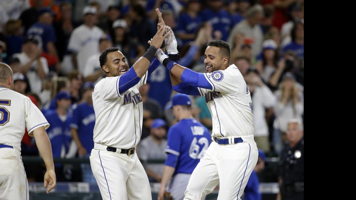 
Franklin Gutierrez, right, greets Mariners teammate Nelson Cruz as he crosses home on his home run to defeat the Toronto Blue Jays in the 10th inning Sunday.
