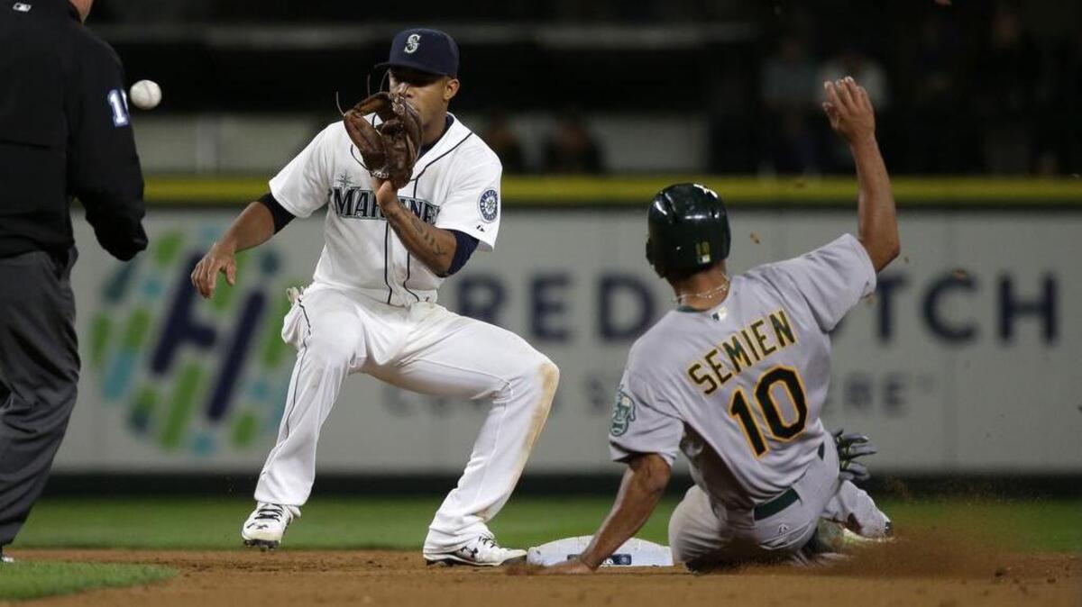 
Mariners shortstop Ketel Marte, left, makes the catch before tagging out the Athletics’ Marcus Semien as he tries to steal second base in the eighth inning Saturday. Semien ended up hitting the game-winning home run in the 13th inning as the A’s won, 7-5.
