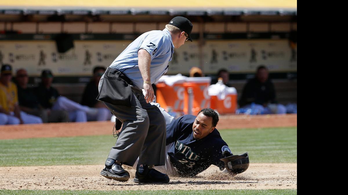
The Mariners’ Nelson Cruz slides home beside umpire Mike Muchlinski in the sixth inning Sunday. Cruz scored on Seth Smith’s two-run single.

