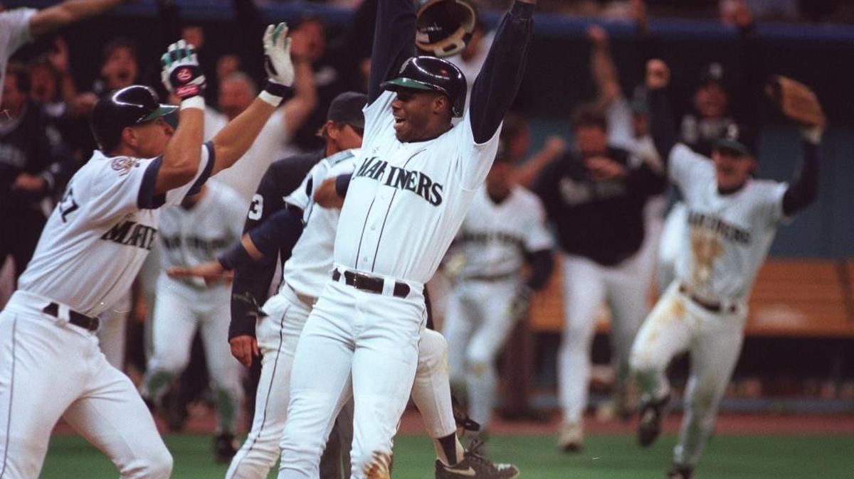 Seattle Mariners’ Ken Griffey Jr. leaps after crossing home plate as the winning run in the bottom of the 11th inning as New York Yankees’ catcher Mike Stanley awaits the ball on Oct. 8, 1995 in Seattle. Seattle won 6-5.