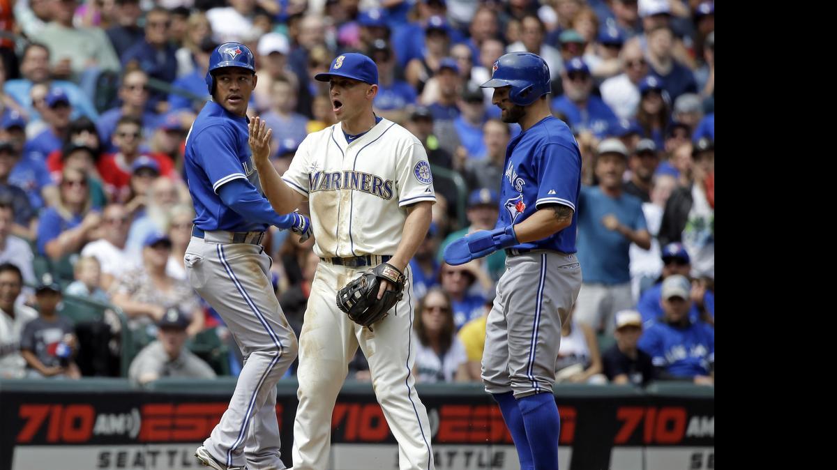 
Mariners third baseman Kyle Seager, center, yells for catcher Mike Zunino, not pictured, to come at Toronto Blue Jays Ezequiel Carrera, left, and Kevin Pillar during a rundown in the fourth inning Sunday at Safeco Field. Carrera eventually lost his footing and was tagged out by Zunino to complete an unusual triple play.
