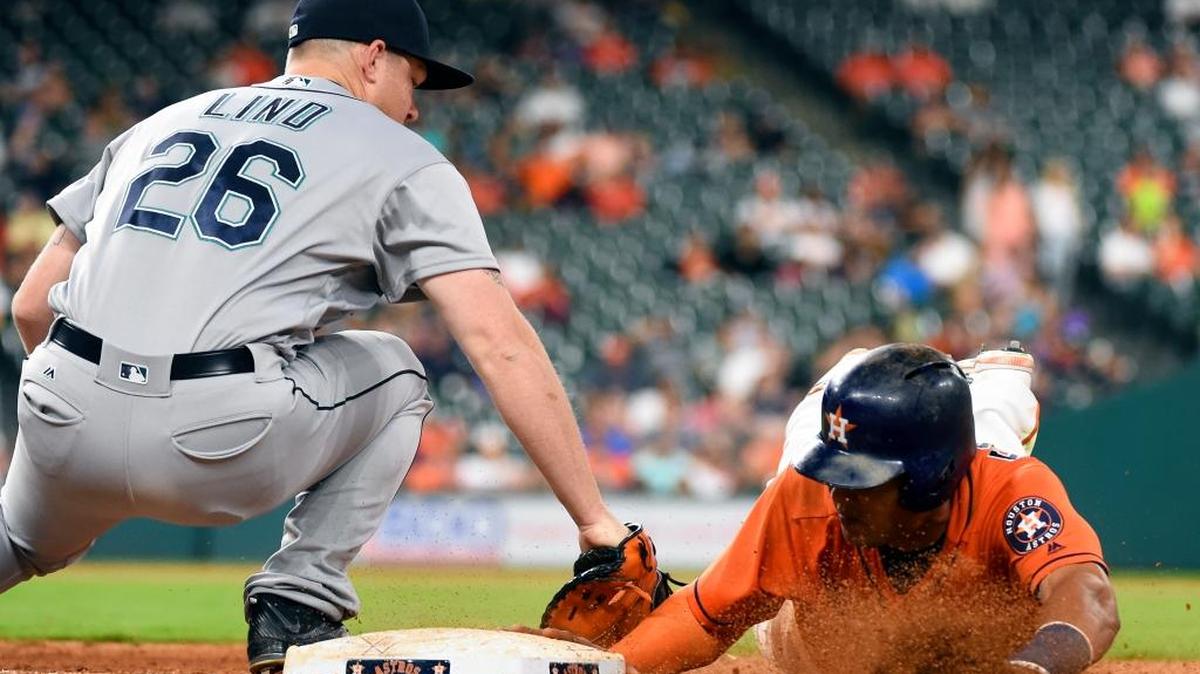 Houston Astros’ Carlos Gomez, right, beats the pickoff tag of Seattle Mariners first baseman Adam Lind (26) in the eighth inning of a baseball game, Friday, May 6, 2016, in Houston.