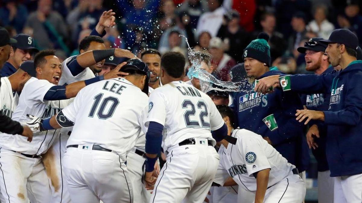 Seattle Mariners’ Dae-Ho Lee (10) is greeted at the plate by teammates after he hit a walk-off two-run home run in the 10th inning of a baseball game against the Texas Rangers, Wednesday, April 13, 2016, in Seattle. The Mariners beat the Rangers, 4-2.