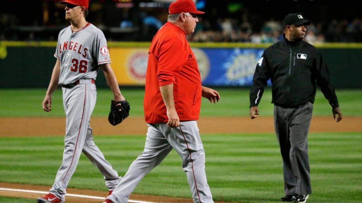 
Angels starting pitcher Jered Weaver, left, walks off the field as manager Mike Scioscia, center, walks out to talk to home plate umpire Brian O’Nora, not seen, after O’Nora ejected Weaver from for hitting the Mariners’ Kyle Seager with a pitch in the fifth inning Wednesday.

