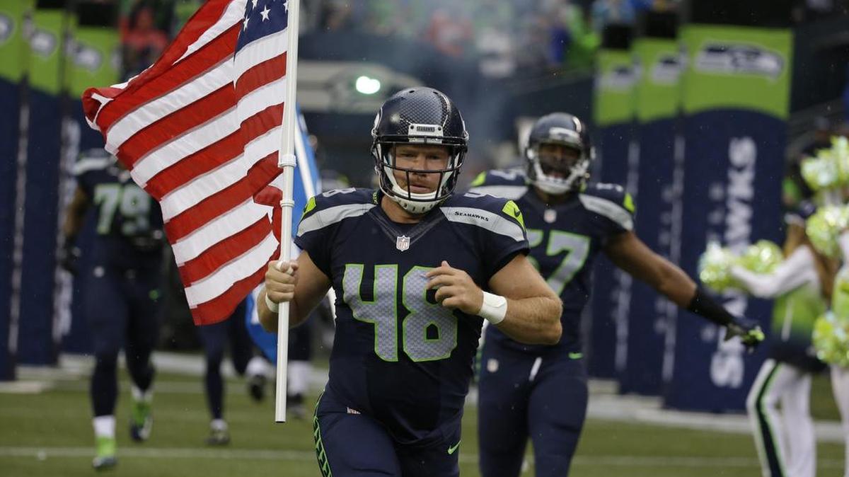 
Former Seahawks long snapper and military veteran Nate Boyer runs out of the tunnel Friday at CenturyLink Field with an American flag before the team’s exhibition opener against the Denver Broncos. Boyer was released by the Seahawks on Tuesday to make way for quarterback Jake Waters.
