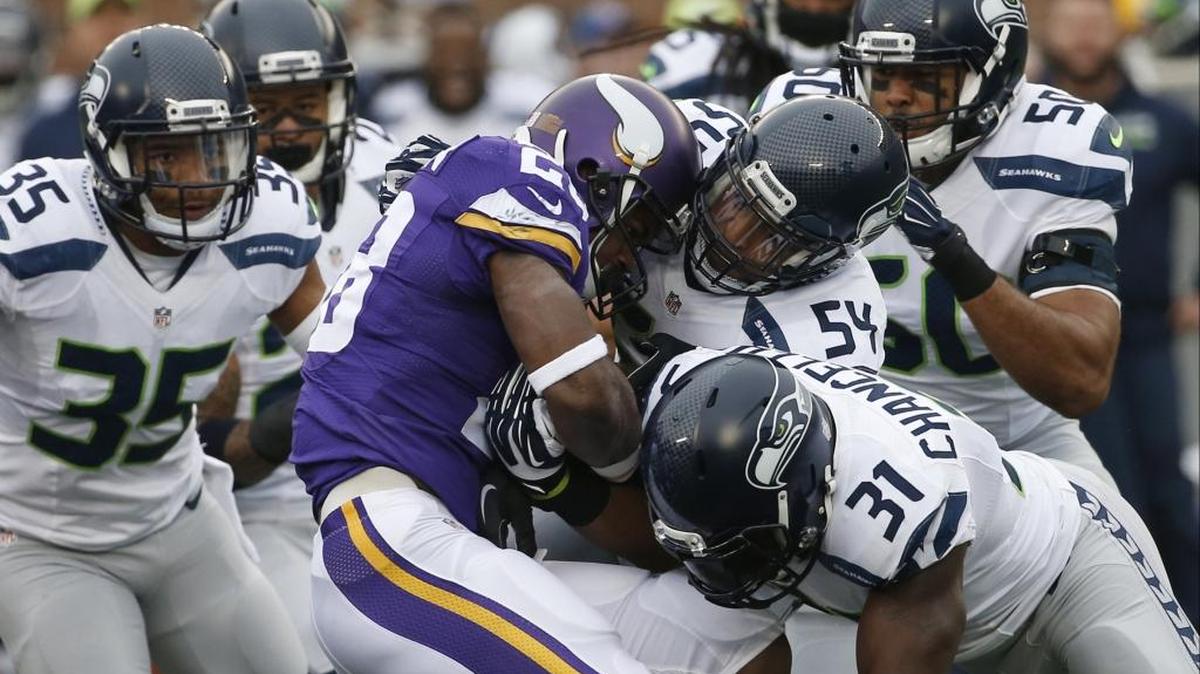 Vikings running back Adrian Peterson (28) is stopped by Seahawks defenders including linebacker Bobby Wagner (54) and strong safety Kam Chancellor (31) in Seattle’s 38-7 win at Minnesota on Dec. 6.