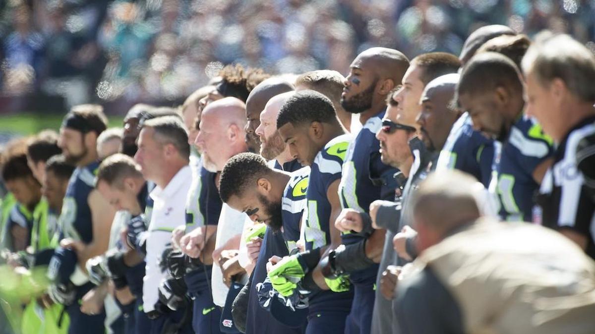 Seahawks safety Earl Thomas bows his head as he stands arm-in-arm with teammates and team staff during the national anthem before Sunday’s NFL season opener against the Miami Dolphins at CenturyLink Field in Seattle.