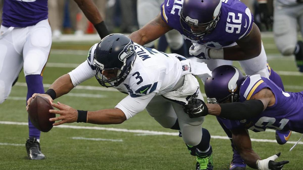 Seattle Seahawks quarterback Russell Wilson (3) dives for a eight-yard touchdown run as Minnesota Vikings cornerback Antone Exum (32) defensive tackle Tom Johnson (92) try to bring him down in the first half of an NFL football game Sunday, Dec. 6, 2015 in Minneapolis.