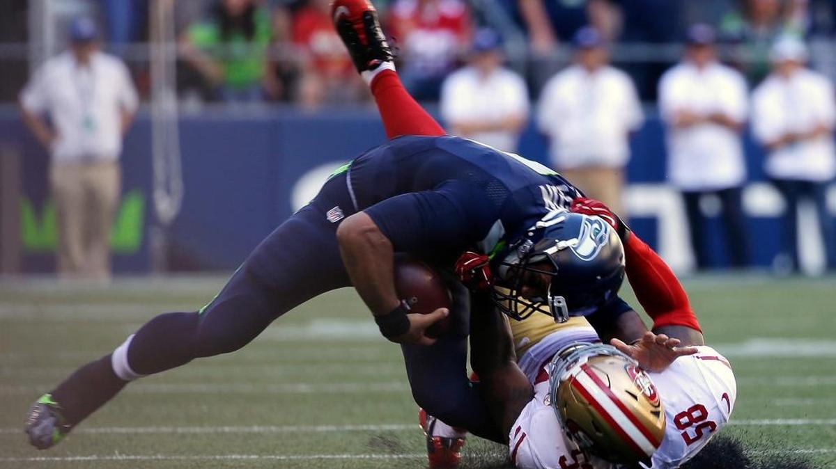Seattle Seahawks quarterback Russell Wilson, top, is pulled down by San Francisco’s Eli Harold in the second half on Sunday, Sept. 25, 2016, in Seattle.