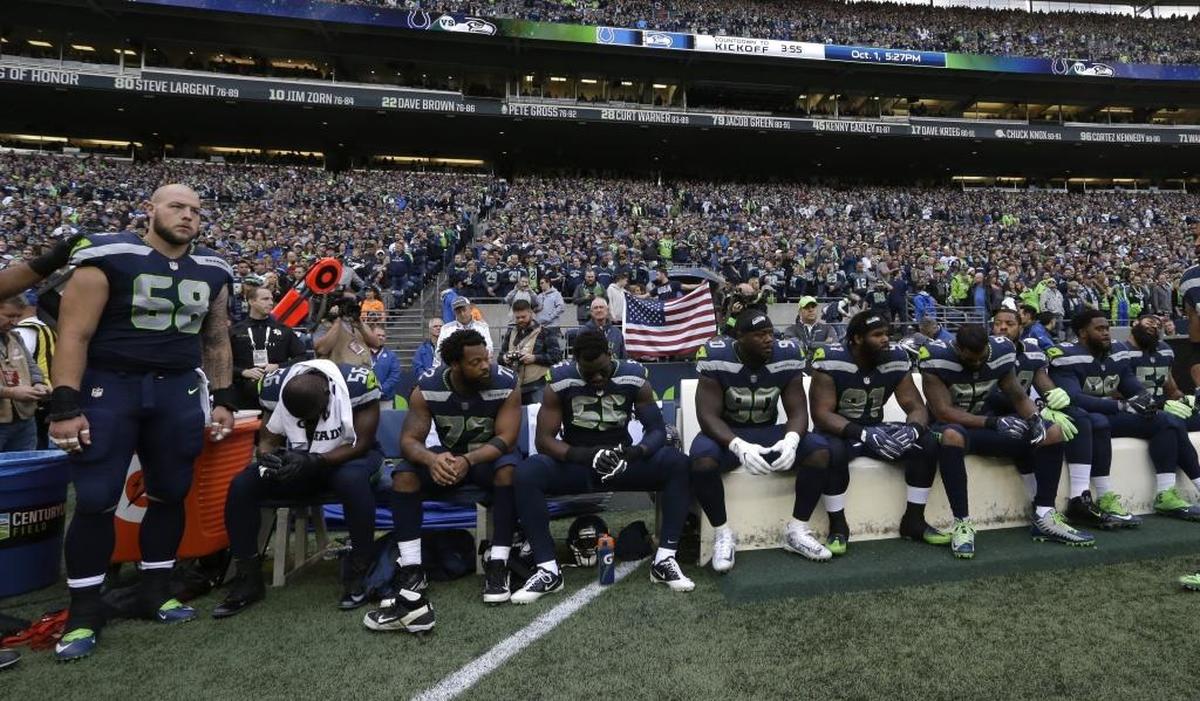 Seattle Seahawks players, including defensive end Michael Bennett, third from left, sit during the singing of the national anthem before their game against the Indianapolis Colts on Oct. 1, 2017, in Seattle.