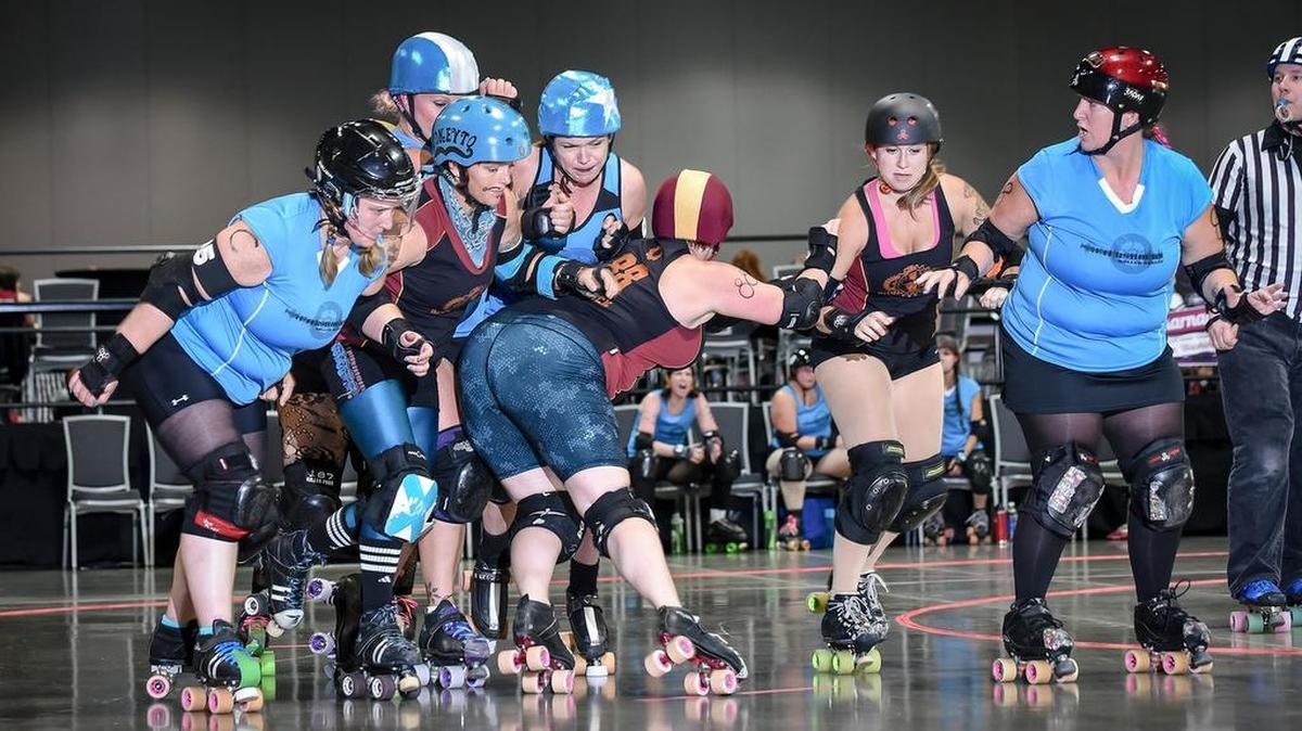 
Luna Tick from team Cog Blockers holds back her opponent with the help of teammate Pokeyto Mustachio at the roller derby tournament Spokarnage. 
