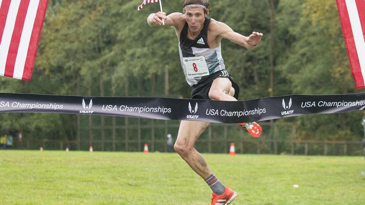 Andy Wacker kicks through the finish line ribbon as he takes first place among men in the USATF Half Marathon Trail Championships at the Lake Padden Trail Half Marathon on Saturday, Oct. 15, at Lake Padden in Bellingham.