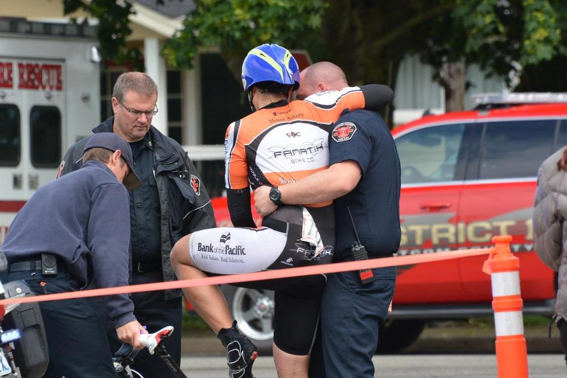 Medics help cyclist Michael Finley, the cyclist with the Boomer’s Drive-In team, who finished his road bike leg with a police escort after he crashed and dislocated his shoulder about 15 miles from Everson, Wash., during the Ski to Sea Race on Sunday, May 29, 2016.