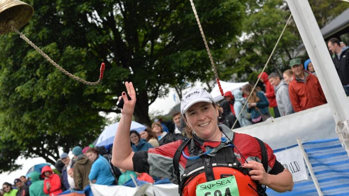 Meg Kelly, of team Car Pay Die ‘Em, rings a bell after crossing the finish line at the 2014 Ski to Sea Race.