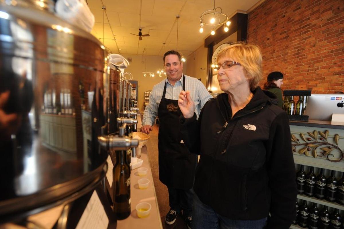 Co-owner Ross Driscoll watches while customer Patty Reddick samples some of the 70 olive oils and vinegars that he sells at the recently expanded Drizzle Olive Oil & Vinegar Tasting Room in Fairhaven in March 2013.