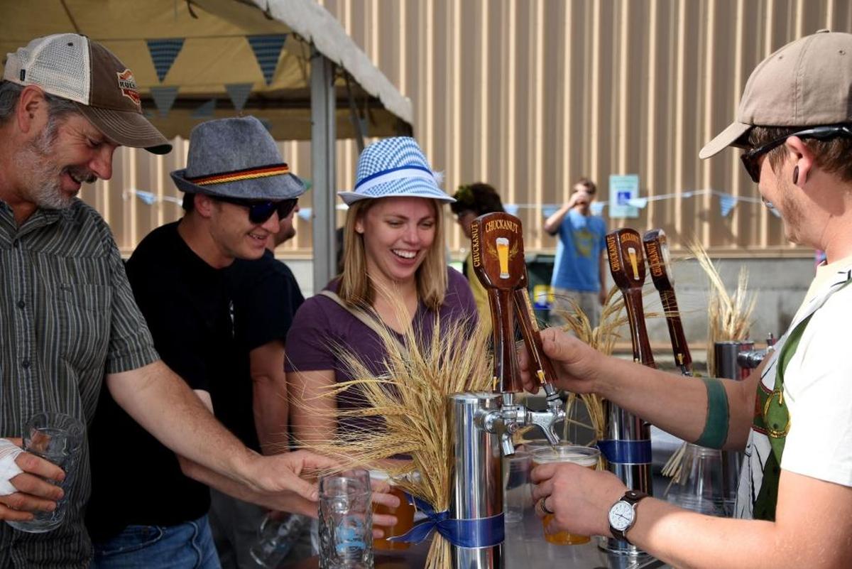 Bill Rink, Adam Hagen and Paige Hagen wait as their drinks are refilled at the outdoor tap set up the Octoberfest celebration at Chuckanut Brewery in September 2016.