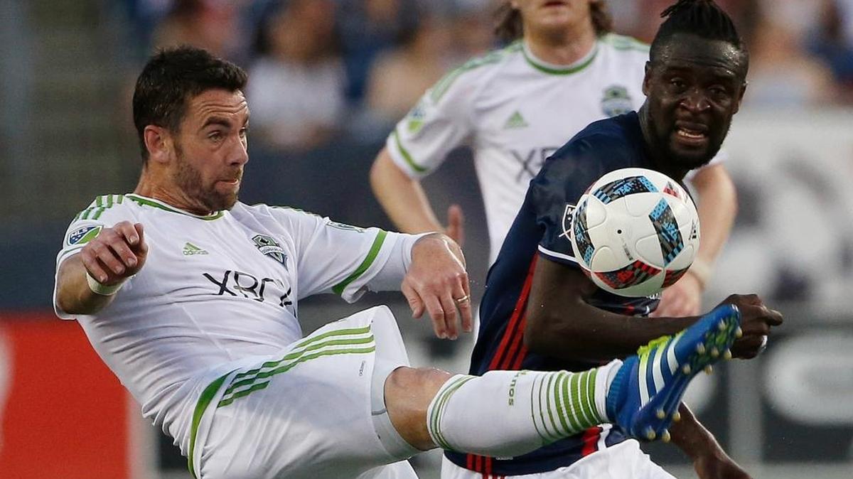 Seattle Sounders's Zach Scott, left, and New England Revolution's Kai Kamara battle for the ball during the first half of an MLS soccer game Saturday, May 28, 2016, in Foxborough, Mass. The Revolution won 2-1.