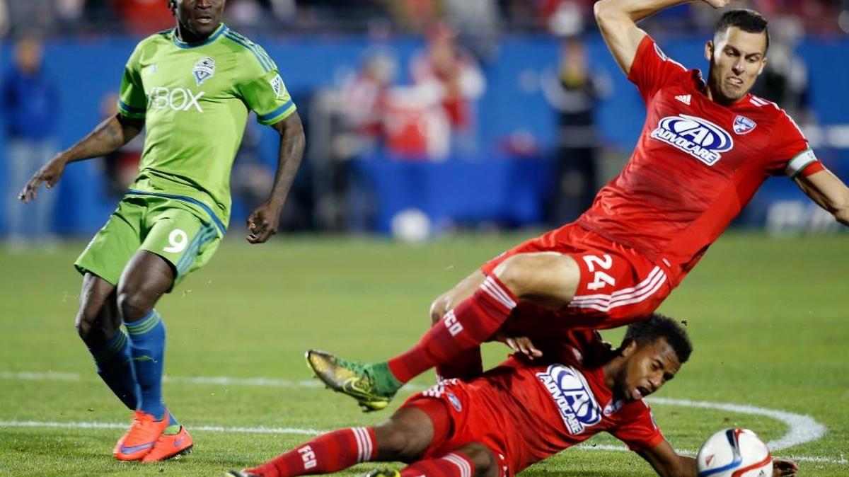 FC Dallas defender Matt Hedges (24) and midfielder Kellyn Acosta, bottom, collide while trying to break up a pass intended for Seattle Sounders FC forward Obafemi Martins (9) during the first half of an MLS soccer western conference semifinal playoff match Sunday, Nov. 8, 2015, in Frisco, Texas.