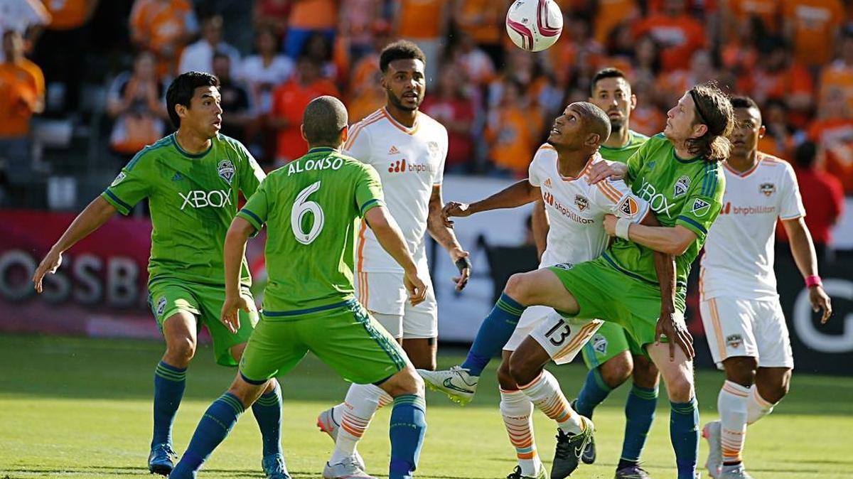
Sounders midfielder Erik Friberg, center right, battles for the ball with Houston’s Ricardo Clark on Sunday in Houston.
