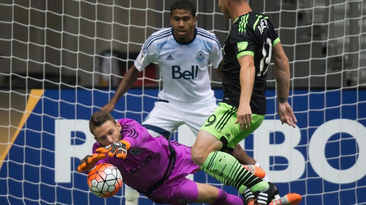 
Vancouver Whitecaps goalkeeper Paolo Tornaghi, bottom left, dives to keep the ball away from Seattle Sounders' Chad Barrett, right, as Whitecaps' Ethen Sampson, back, defends during the first half of the teams’ 1-1 draw in a CONCACAF Champions League matchup Wednesday in Vancouver, B.C.
