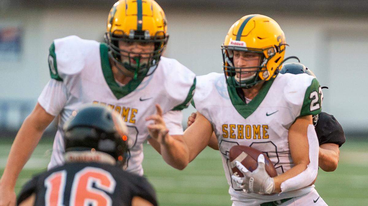 Sehome running back Tommy Funk (22), right, looks for an opening as offensive lineman Coleton Heinze (70) preps to block Blaine defensive back Jesse Deming to make a short gain during the first quarter on Friday evening Sept. 9, at Blaine High School in Blaine.